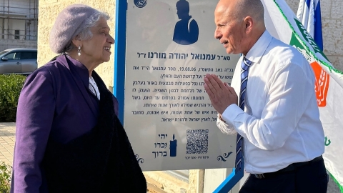 ראש העיר ואימו של עמנואל מורנו סליביה על רקע שלט ההסבר להנצחתו.jpg