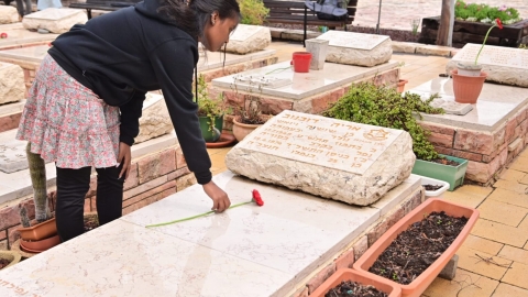 תלמידה מניח פרח על קברו של החלל.jpg