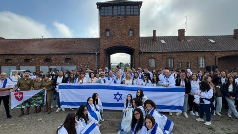 המשלחת והתלמידים על רקע הכניסה לבירקנאו.jpg